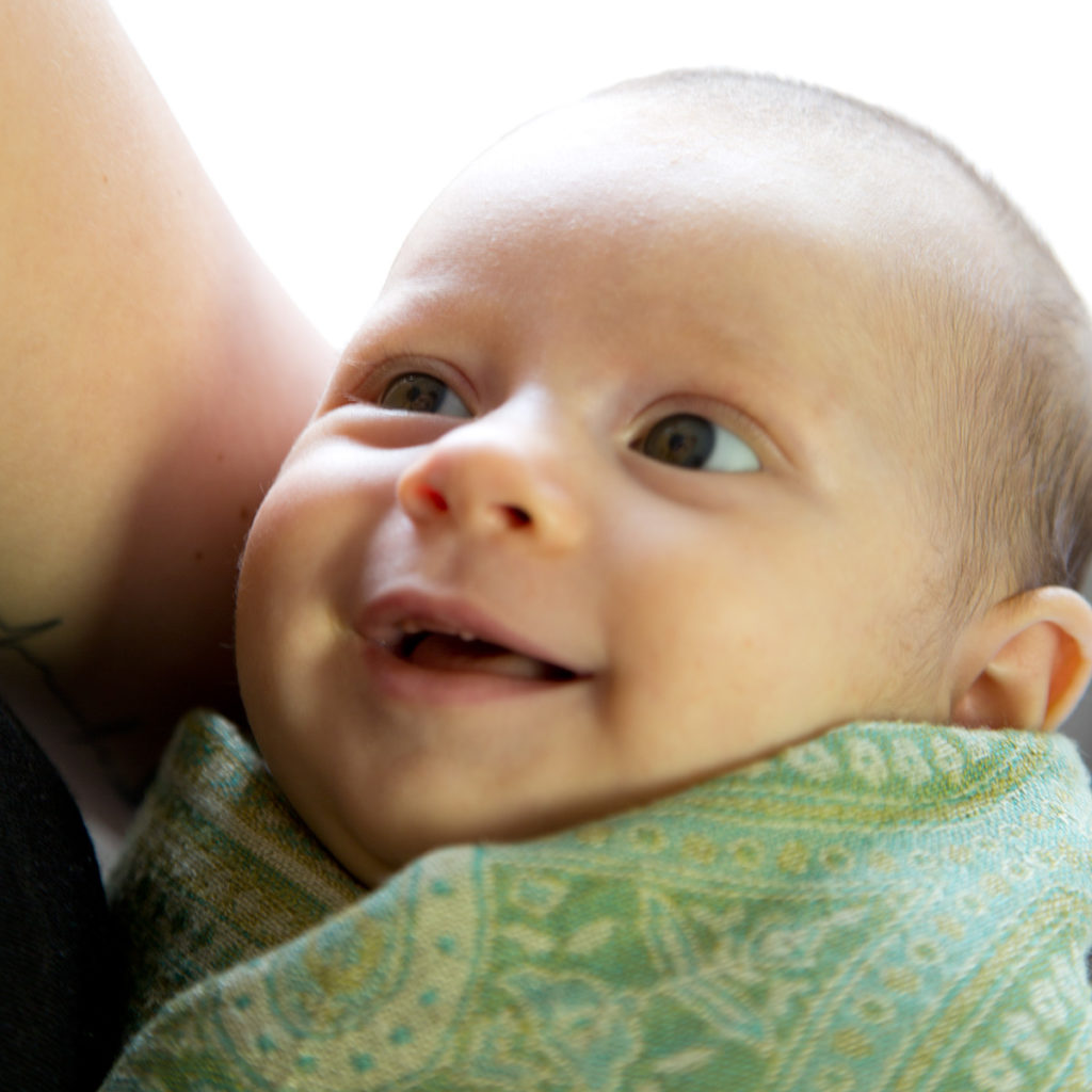 lächelndes, gepucktes Baby im Arm gehalten